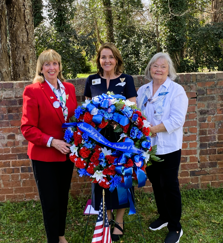 three women holding patriotic wreath